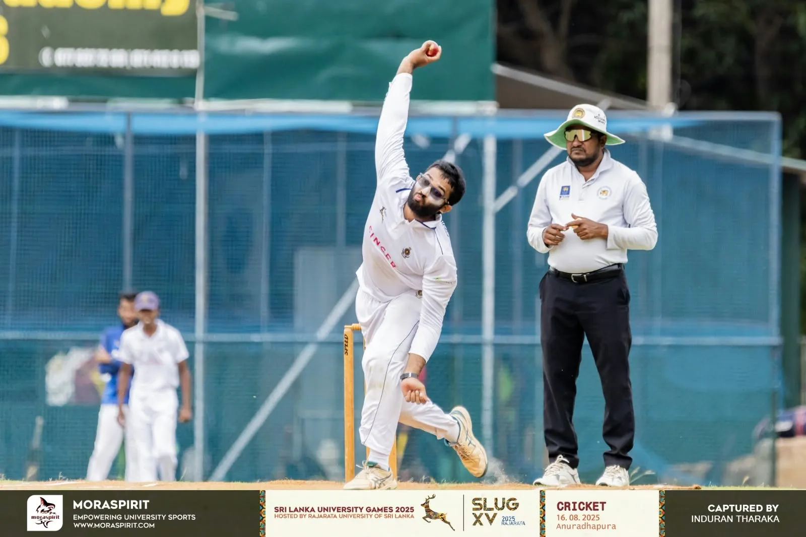 Muftee in his delivery stride, ball cocked behind his head, the umpire watching from square