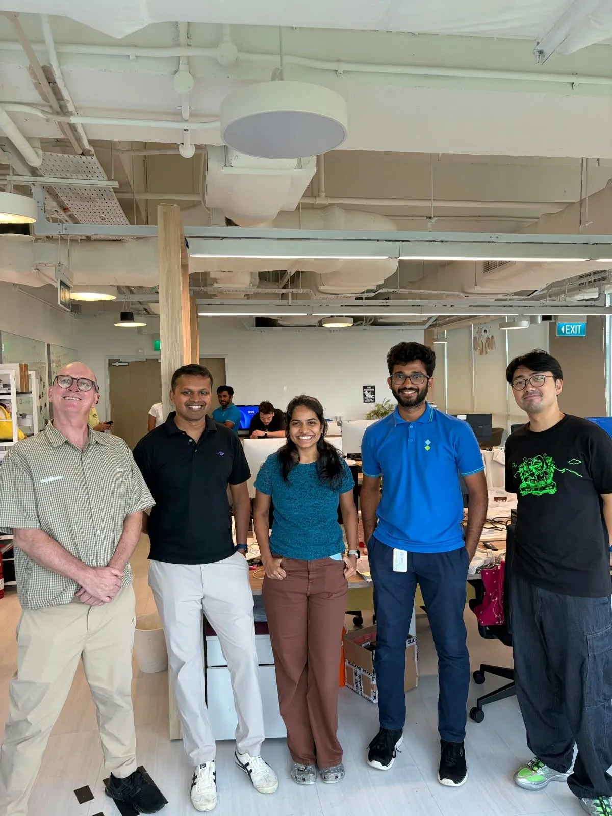 The OpenGUT team standing together in the lab, workbenches and prototypes behind them